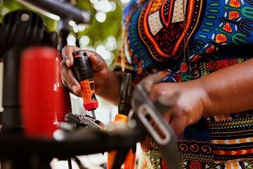 Detailed shot of female african american arm arranging an assortment of professional equipments for bicycle maintenance. Image showing close-up view of hand of black woman holding screwdriver.