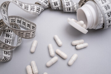 Measuring tape and tablets, vitamins on a colored background with space for text. Concept of losing...