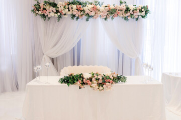 The bride and groom's table decorated with flowers and candles in a restaurant. Roses decorate the table of the bride and groom at a festive banquet