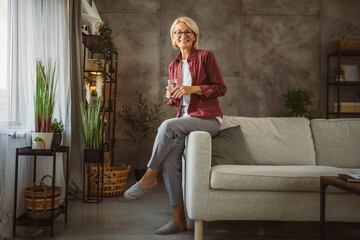 Obraz premium Portrait of beautiful mature senior woman sit and hold glass of water