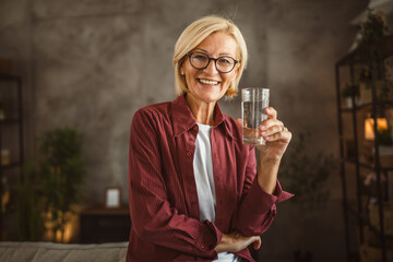 Portrait of beautiful mature senior woman sit and hold glass of water