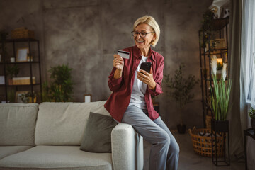 Mature senior woman buy online on mobile and use credit card