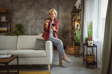 Obraz premium Mature senior woman buy online on mobile and use credit card