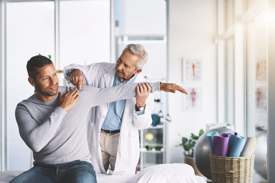 Doctor, man and patient with stretching for shoulder pain with physical therapy, healthcare or body recovery. Orthopedic, physician or medical expert for arm rehabilitation with examination or advice