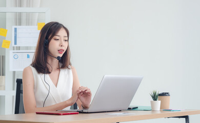 Employee woman girl asian one person smile happy enjoy sitting chair on desk looking talk telephone and hand holding notebook laptop ready for business service call center working job in room office