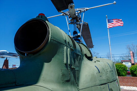 right rear of UH-1 Iriquois helicopter with engine exhaust and rots showing with flag in the background
