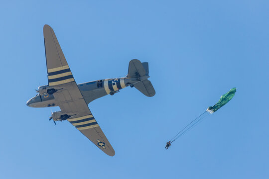 parachutists jump out of a vintage C-47 transport at an aerial display
