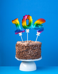 Air balloon number 104 - Birthday cake on blue background