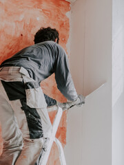 A Caucasian young man is putting putty on the wall.