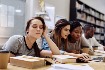 Bored, burnout and face of unhappy student with books in library for education, learning or study. Annoyed. exhausted and tired with face of girl at desk of college or university for classroom lesson
