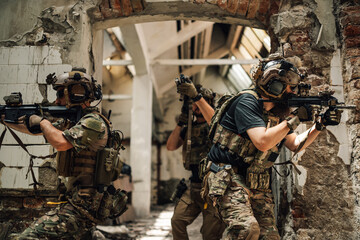 Group of air soft fighters in action attacking opponent in ruined building