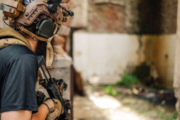 Air soft player with weapon is hiding in abandoned ruined building.