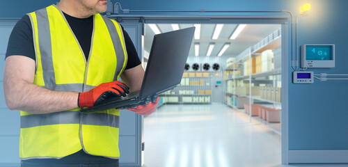 Worker near industrial refrigerator. Employee in freezing warehouse. Cropped man adjusts industrial...