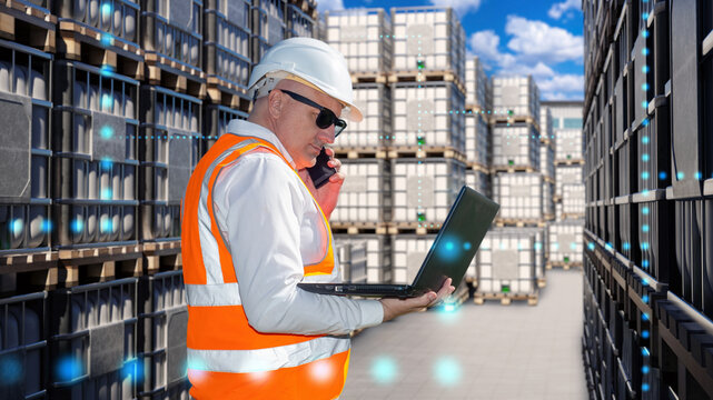 IBC containers near man. Logistician with laptop and phone. Street storage tanks on pallets. IBC containers for oil transportation. Man worker keeps records of production. Guy negotiates sale of IBC