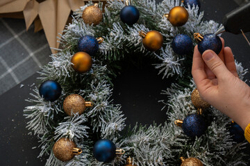 Crafter using hot glue DIY process of woman making Christmas arrangement with decor of blue and...