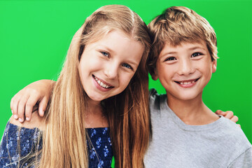 Siblings, smile and portrait in studio, embrace and together with love, family or cheerful for school. Hug, girl and boy in green background, happy or kids with confidence for first day in elementary