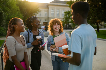 Interracial students at campus smiling at chatting on a coffee break.