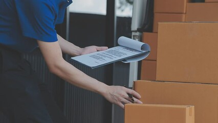 Young cheerful delivery man with parcel near car full of cardboard boxes, full length shot. Shipping service concept