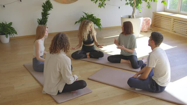 Create a tranquil environment by engaging in group meditation and discussion in a welllit room with beautiful plants for a serene and peaceful atmosphere, promoting health and wellbeing