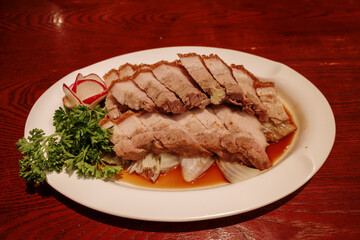 Selective focus, sliced crispy belly pork served on white plate.