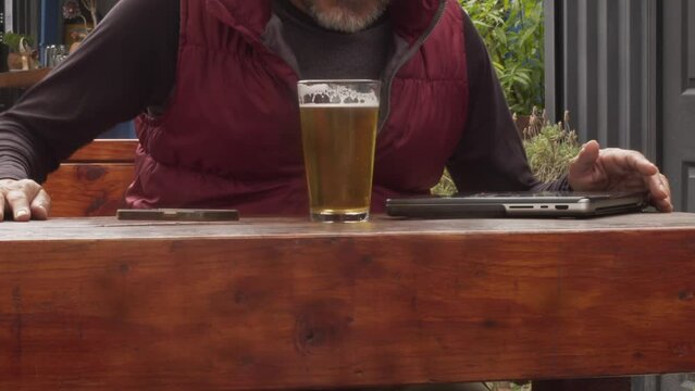 Hombre  bebe  cerveza artesanal  en un bar mientras trabaja