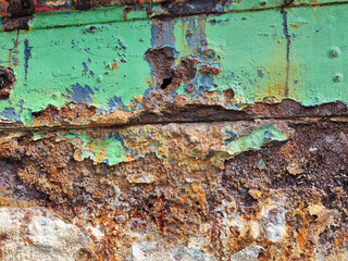 Corroded steel hull plating on a ship. Green paint over very rusted steel that is flaking off