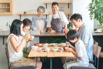 Obraz premium 家のダイニングで家族団欒して食事する子供と夫婦・親子・三世代家族（二世帯住宅） 