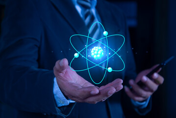Bussinessman hand holding creative atom on blue background. Nuclear fusion concept, endless energy,...