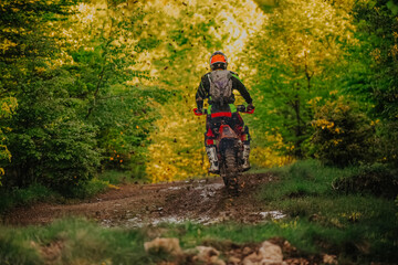 Professional enduro bike rider on action, dirt ride on the muddy road. Motocross sport.