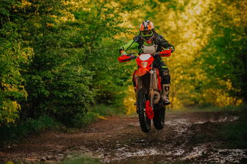 Professional enduro bike rider on action, dirt ride on the muddy road. Motocross sport. © Malik Nalik