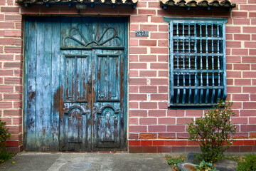 Timeworn Charm: A Rustic Brick Facade with Weathered Wooden Door