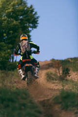 Professional enduro bike rider on action, dirt ride on the muddy road. Motocross sport.