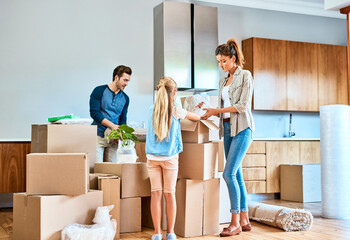 Unpacking, parents and child with boxes in new house for moving, real estate or property investment...