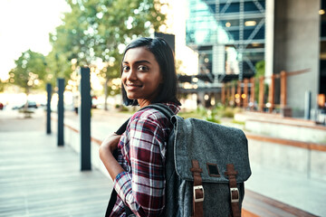 Girl, university student and walk with backpack, portrait and smile for education in city. Indian person, happy and outdoor on sidewalk for learning, development and scholarship for future in London