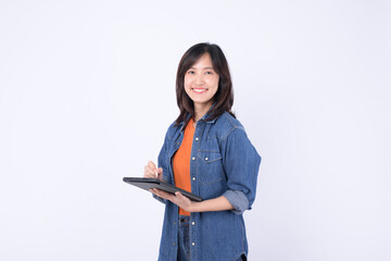 An Asian woman wearing orange shirt and denim jean jacket is holding a tablet and a stylus against...