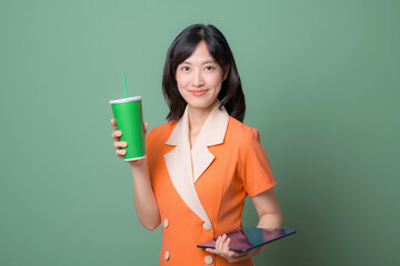 A young woman in an orange dress with white accents stands against a green background. smiles...