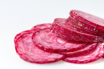 Fototapeta premium Close-up of fresh, vibrant red beetroot slices on a white background, showcasing the natural texture and color of the vegetable.