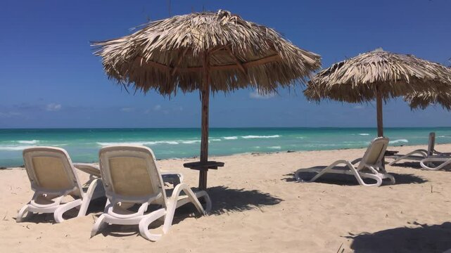 Sand beach and straw umbrellas in Varadero, Cuba with sunbeds and blue ocean