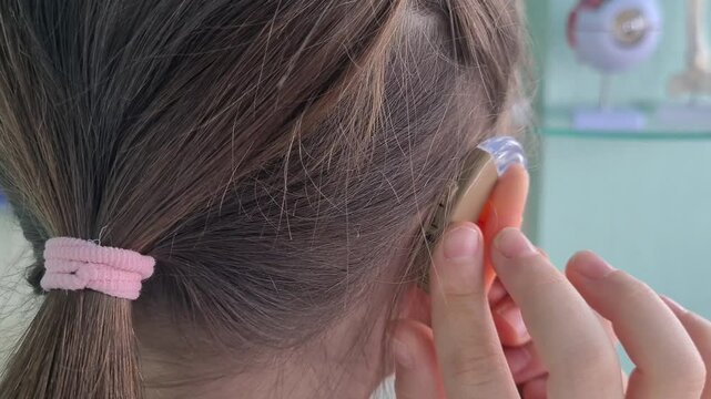 Young Girl Adjusting Hearing Aid in a Medical Setting
