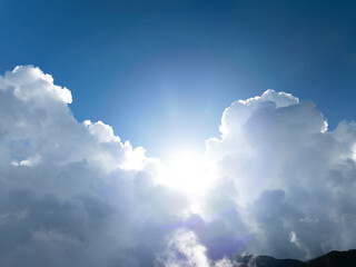 Fototapeta premium The sun shining through the puffy clouds above mountain