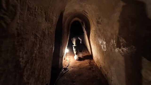People enter Cu Chi tunnel by step down stairs at tunnels door, tourist visit historic heritage sites of Vietnamese War