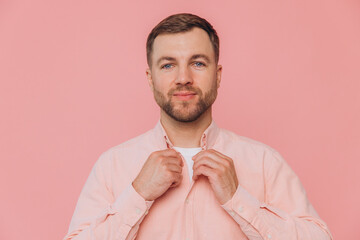 Cute smiling unshaven man in pink shirt posing isolated on pink background
