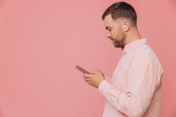 Side view happy caucasian bearded man wear pink shirt casual clothes listen to music in earphones...