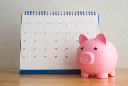Pink piggy bank and white blank calendar with white background. Reminder schedule of savings money, DCA (dollar cost averaging) investment, money management planning concept. Home finance and economy.