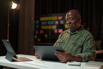 Happy African American man looking at laptop computer screen, typing, searching for information, checking email, chatting on social network. Freelance blogger working on online projects.