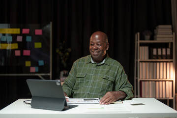 Happy African American man looking at laptop computer screen, typing, searching for information, checking email, chatting on social network. Freelance blogger working on online projects.