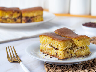 Close-up of a plate with Martabak Manis, an Indonesian sweet pancake filled with cheese and chocolate. Another plate with Martabak is visible in the blurred background.