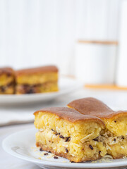Close-up of a plate with Martabak Manis, an Indonesian sweet pancake filled with cheese and chocolate. Another plate with Martabak is visible in the blurred background.
