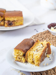Close-up of a plate with Martabak Manis, an Indonesian sweet pancake filled with cheese and chocolate. Another plate with Martabak is visible in the blurred background.