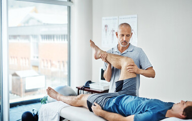 Obraz premium Physiotherapy, men and client with recovery, leg pain and healing with wellness, service and expert with skill. People, physical therapist or customer with injury, health and trust with consultation